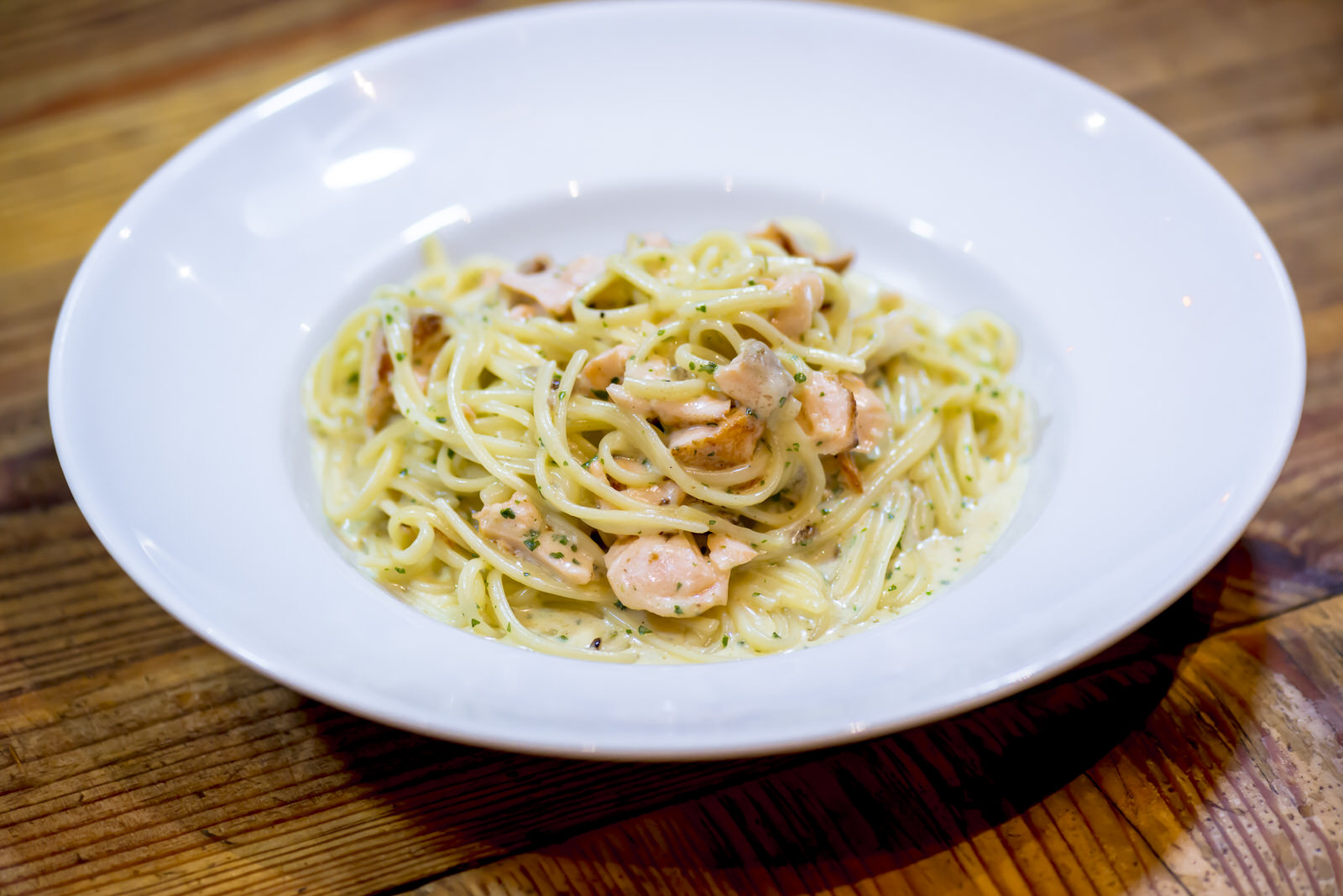 Des spaghetti au saumon dans une assiette blanche